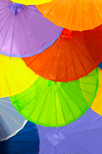 10 parasol umbrellas overlapping, colorful background, purple, orange, yellow, dark orange, blue colors