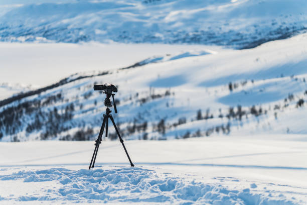 istock Video camera on tripod stands high in mountains filming remote winter hills. Focus on camera with blurry background 2036053735