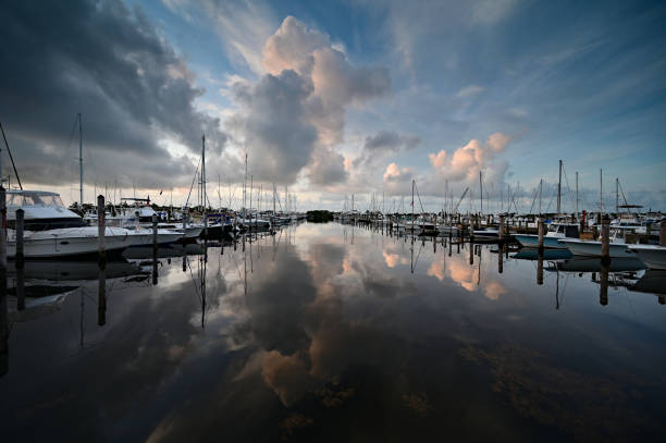 Miami, Florida - 6/12/2021: Bright summer cloudscape reflected in tranquil water of Dinner Key Marina in Coconut Grove.