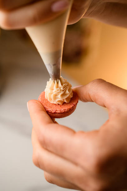 istock Confectioner's hands apply cream to the macaroon blank 2036109938