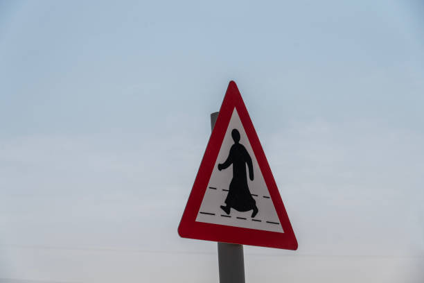 Arabic traffic sign, men in kaftan against sky.