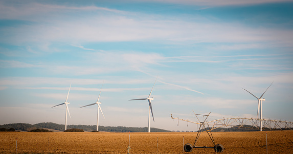 Renewable energies and agriculture: wind turbines on plowed field. automatic irrigation system