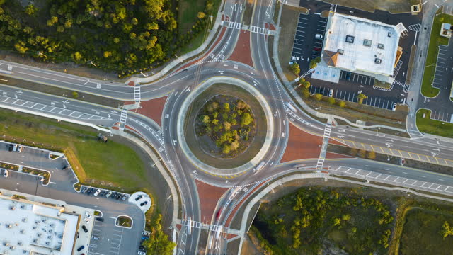 Aerial view of road roundabout intersection with fast moving heavy traffic. Timelapse of urban circular transportation crossroads