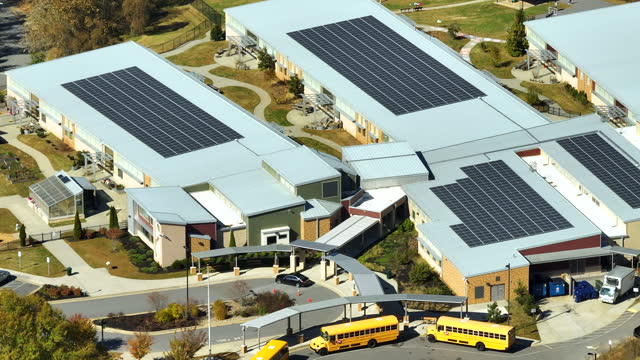 Aerial view of American school building with rooftop covered with photovoltaic solar panels for production of electric energy