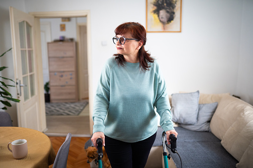 Portrait of happy senior woman in nursing home, standing and holding mobility walker
