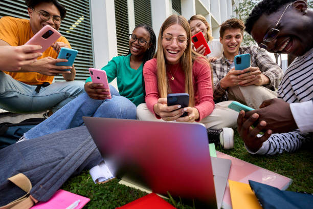 group of young multiracial university students immersed on their mobile cell technology addicted - multi ethnic group concentration mobile phone using laptop imagens e fotografias de stock