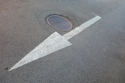 The white arrow is on the asphalt road