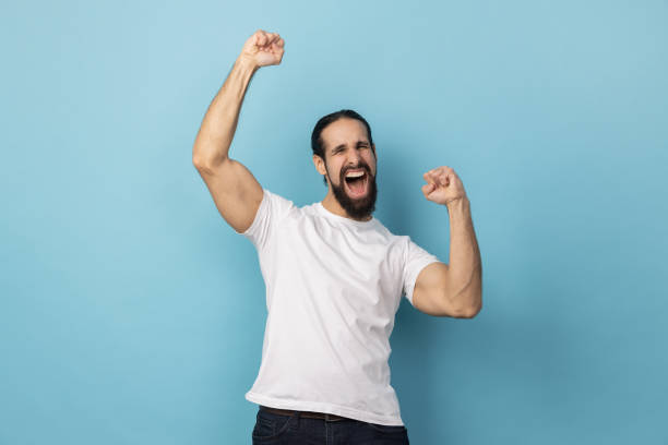 istock Man expressing winning gesture with raised fists and screaming, celebrating victory. 2036397255