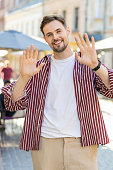 young-man-smiling-friendly-at-camera-waving-hands-hello-hi-greeting-or-goodbye-in-city-street.jpg?b=1&s=170x170&k=20&c=zgWSkpqb7IvwhZKELUhFngHVJiFLmaly1cgr7yaHjCU=