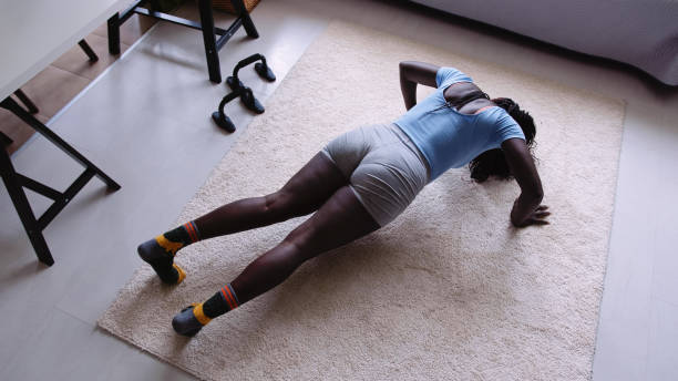 Home workout. Young black woman doing push ups.