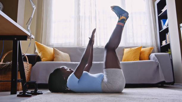 Young black woman doing sit-ups. Training at home.