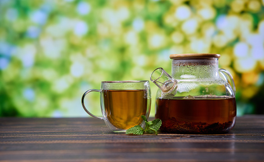 natural organic herbal tea in glass teapot and cup on a wooden table.