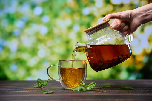 natural organic herbal tea pours in a glass from glass teapot.