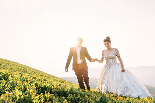 A married couple, bride and groom, kissing at sunset or sunrise on a beautiful tropical beach