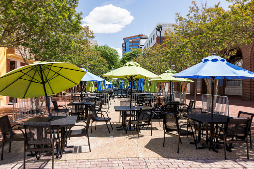 Side walk cafe with colorful umbrellas as sunshade. Weekend activity for Caucasian woman\nand city break in Downtown of Hampton, Virginia