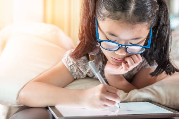 istock School child girl kid using internet online learning on mobile tablet reading looking at digital screen for educational study for Children’s Eye Health and Safety Month and Blue Light Awareness Day 2036416278