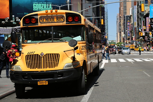 Typical yellow American school bus driving in Manhattan, New York