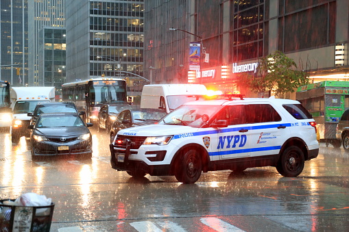 New York Police Department car driving through Manhattan during a downpour with its lights on