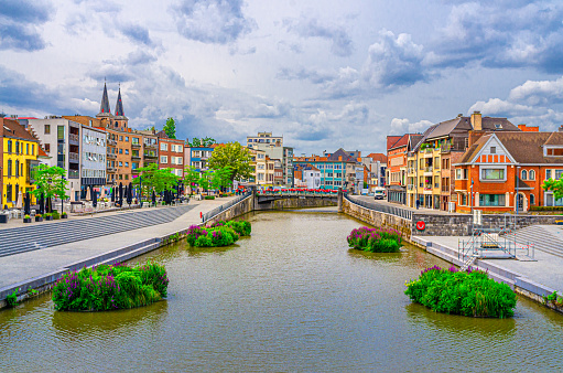 Kortrijk cityscape with embankment of Lys river, bridge across Leie river, plants in water and modern buildings in historical centre, belgium landmark, West Flanders province, Flemish Region, Belgium