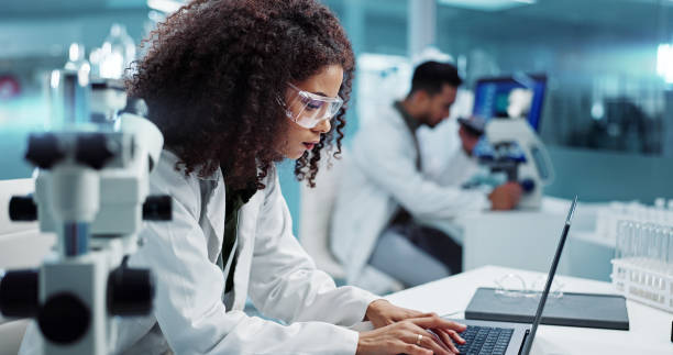 istock Scientist, woman and microscope with computer for laboratory research, test and DNA investigation at night. Professional doctor or science expert with lens check, laptop and particles for inspection 2036497123