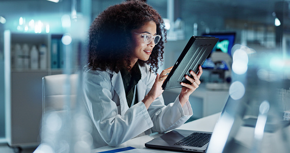 Tablet, laptop and woman scientist in lab working on medical research, project or experiment. Science, career and female researcher with digital technology and computer for pharmaceutical innovation.
