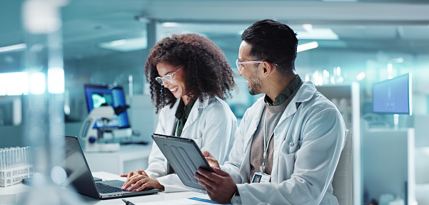 Science, teamwork and laptop with laughing in laboratory for communication, pharmaceutical review or planning. Employees, collaboration and technology for research, discussion and digital analysis