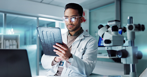 Tablet, scientist and reading for analysis in laboratory, healthcare and online pharmaceutical research . Asian expert, computer and microscope for medicine and information on innovation cure at work