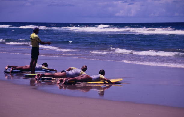 Homem ensinando às pessoas aula de surf na praia - foto de acervo