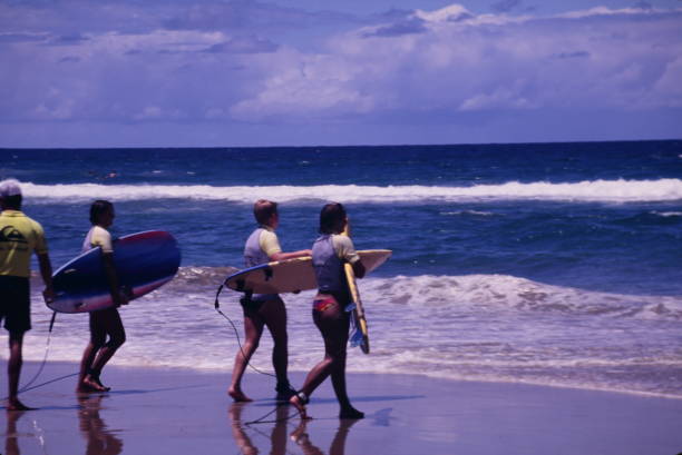Homem ensinando às pessoas aula de surf na praia durante o início dos anos 1990 - foto de acervo