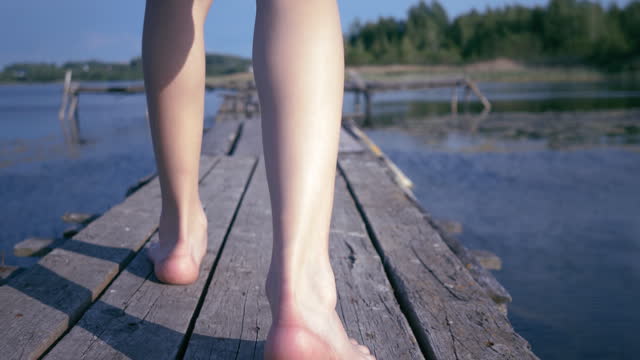 Lakefront Stroll: Close-up of Boy's Feet Walking on Pier Planks