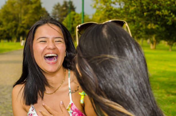 two young female friends sitting on a bench and talking at a public park