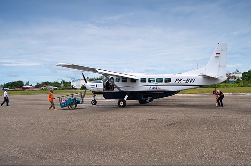 Muara Teweh City, Central Kalimantan Province, Indonesia - April 29, 2019 - Officers carry out the loading and unloading process of airplane passengers' luggage using manual equipment at Muara Teweh City Airport, Central Kalimantan Province, Indonesia.