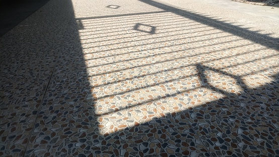 Long shadow of a fence casted on the floor