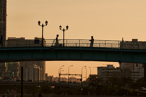 Ho Chi Minh City, Viet Nam 30 Dec 2023: Silhouette of romantic couple walking holding hands on the bridge in the evening. Beautiful sky