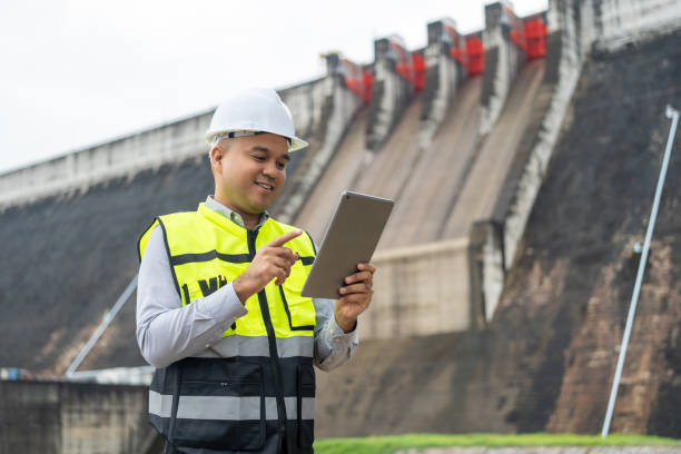 istock Professional asian maintenance engineer man with safety helmet in construction site dam with hydroelectric power plant and irrigation. Manager engineer man working with tablet at project big building. 2036831884
