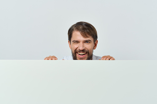 man peeking out from behind banner advertising lifestyle light background. High quality photo