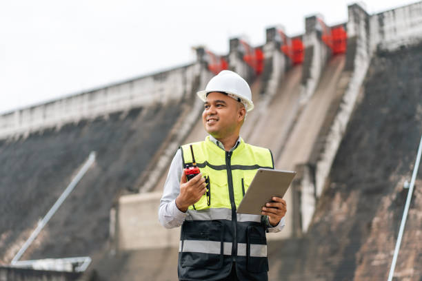 istock Professional asian maintenance engineer man with safety helmet in construction site dam with hydroelectric power plant and irrigation. Manager engineer man working with tablet at project big building. 2036856665