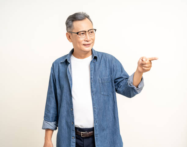 istock Handsome asian mature old man standing pointing finger to blank space isolated white background. Happy Portrait of cheerful smiling senior asian man looking at camera. Mature People and lifestyle 2036862789