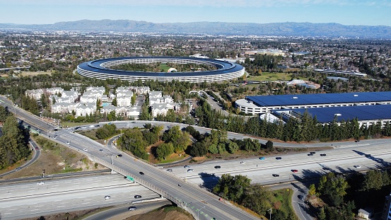 Aerial drone view of Apple Park campus, The Hamptons apartments, vehicle traffic on highway I-280 and Wolfe road interchange in Silicon Valley - Cupertino, California, USA - January 7, 2024