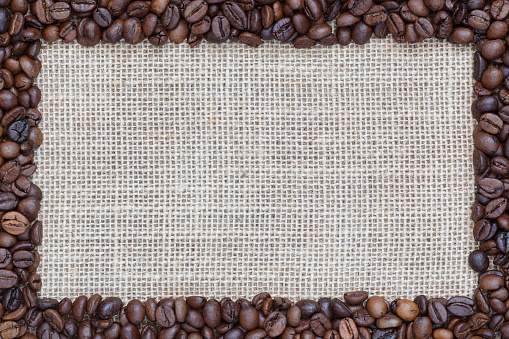 Burlap background with coffee beans in the form of a frame.