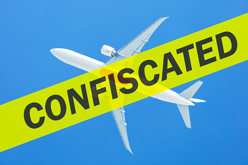 Rupture of the aircraft leasing agreement, confiscation. Aeroplane flying in blue sky and text CONFISCATED