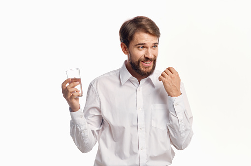 happy man drinks water from a glass on a light background white shirt portrait model. High quality photo