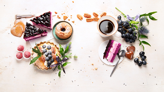 Holiday cake with cup of coffee and grape on light wooden background. Top view, copy space