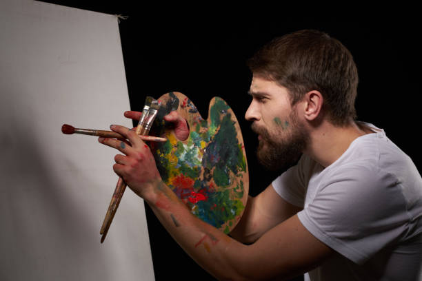 istock A man with a palette in his hands brush easel art Creative approach hobby dark background 2037028544