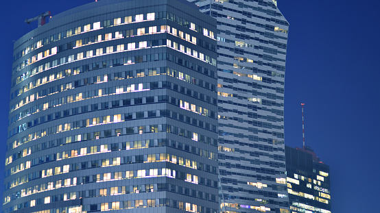 Big glowing windows in modern offices buildings at night. In rows of windows light shines.