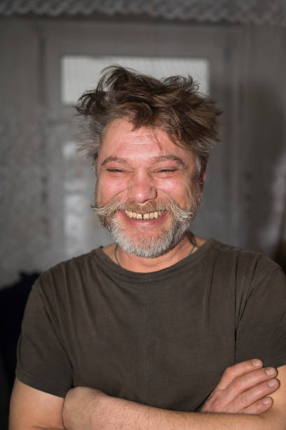 a man with a beard and mustache is smiling with his arms crossed . High quality