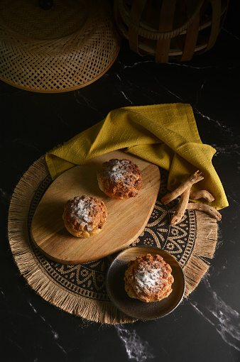 luxury home made chilled vanilla cream puff pastry choux with sugar powder on wood plate and cloth in black background and bamboo basket prop dessert halal menu for cafe