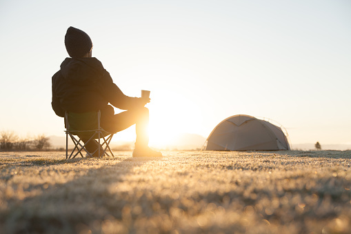 a man enjoying his morning coffee while gazing at the sunrise in the campground