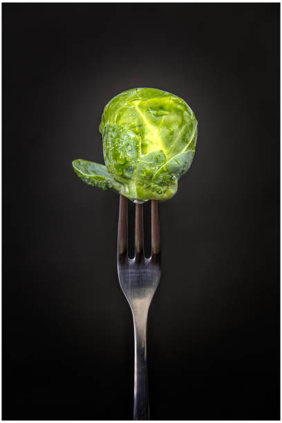 fresh brussel sprout on a fork, detail and close up - brusselsprouts imagens e fotografias de stock