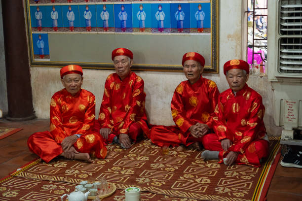 Bac Ninh, Vietnam 02,25,2024 Elderly men wearing red shirts sit in the temple preparing for the ceremony